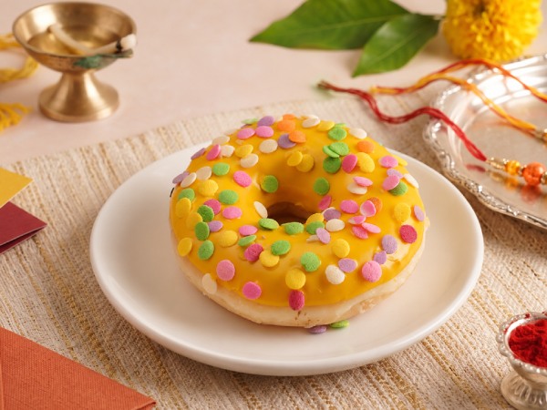 Choco Caramel Luxe doughnut covered in yellow ganache and colourful sugar confetti for celebrations